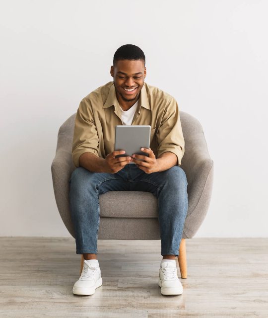 happy-african-man-using-digital-tablet-sitting-ove-2021-09-02-17-14-23-utc.jpg